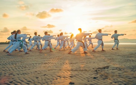 A group of people doing karate on a beach